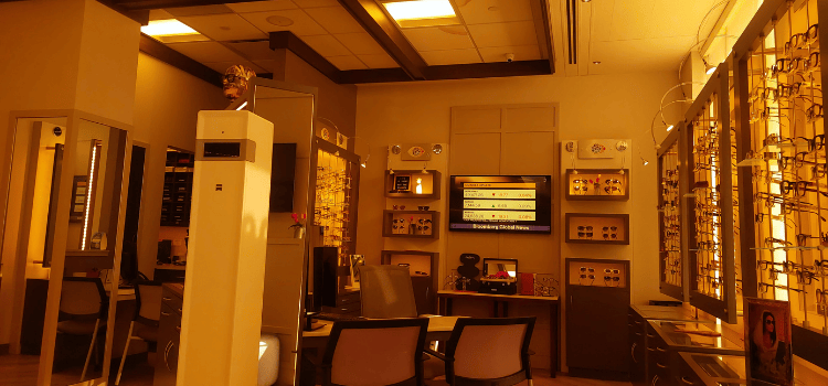 Modern optical store interior with glasses, frames, mirrors, and wall-mounted TV screens