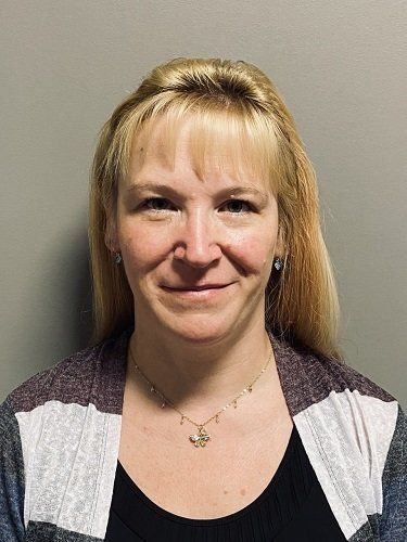 A woman wearing a necklace and earrings is smiling for the camera.