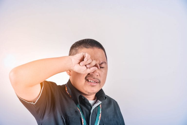 A man is covering his eyes with his hand.