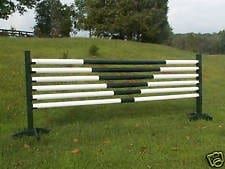 A jumping fence is sitting in the middle of a grassy field.