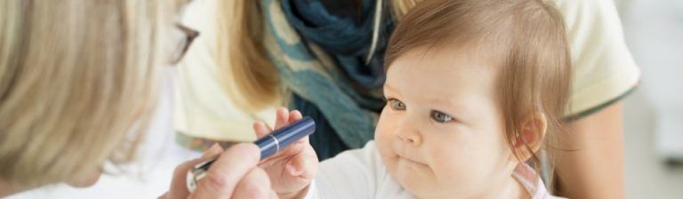 A woman is applying makeup to a baby 's face.