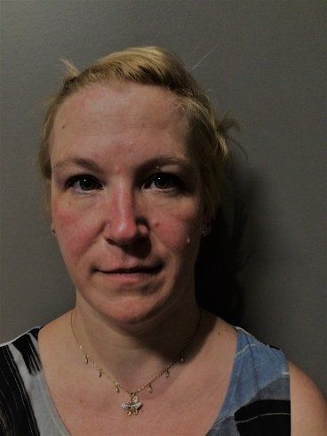 A woman wearing a necklace and earrings is smiling for the camera.