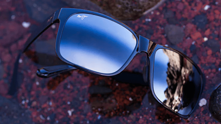 A pair of sunglasses with blue lenses and bi gradient mirror are sitting on a table.