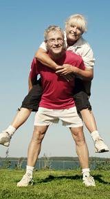 A man is carrying a woman on his back in a field.
