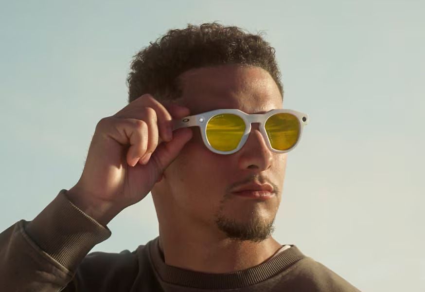 A man is wearing a pair of meta oakley sunglasses with yellow lenses.