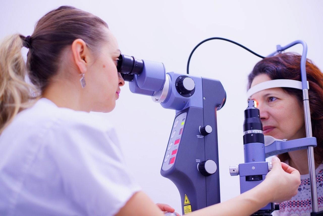 A woman is looking through a microscope at another woman 's eye.