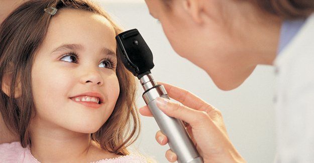 A little girl is getting her eyes examined by a doctor.
