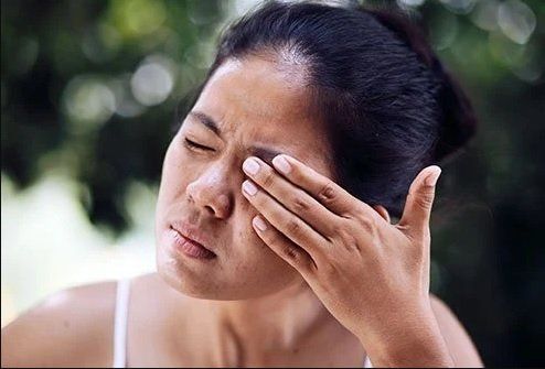 A woman is rubbing her eye with her hand.