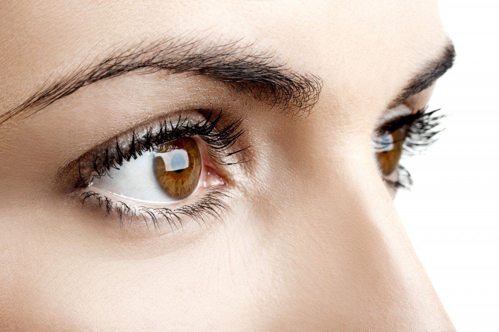 A close up of a woman 's brown eye with long eyelashes.