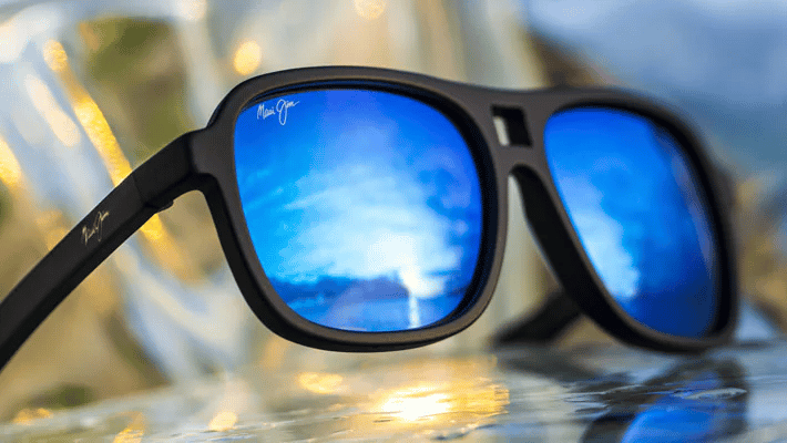 A pair of sunglasses with blue lenses mirror are sitting on a table.