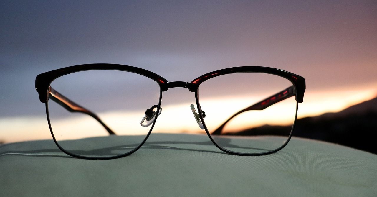 A pair of glasses are sitting on a table with a sunset in the background.