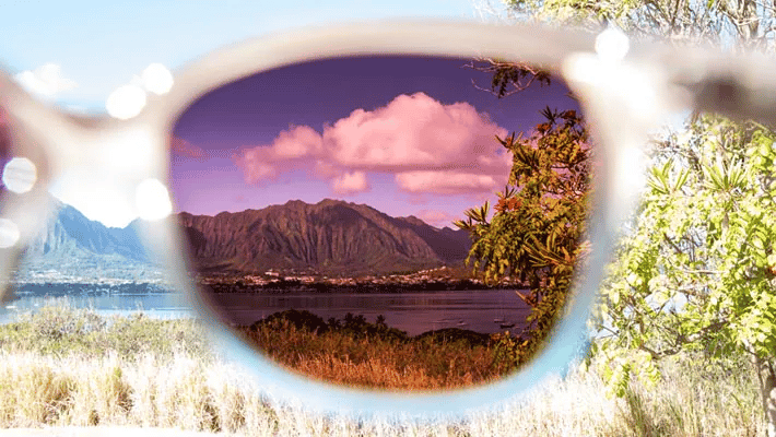 A pair of sunglasses with a reflection of a mountain in the lens.