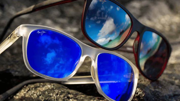 Two pairs of sunglasses are sitting on top of each other on a rock.