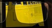 A person is looking at a picture of a yellow bus through a pair of glasses.