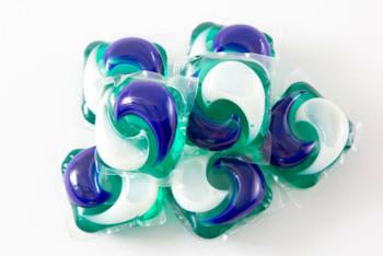 A bunch of purple and green laundry detergent pods on a white surface.