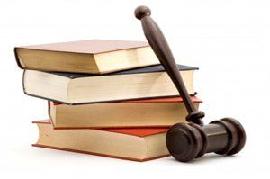 A wooden gavel is sitting on top of a stack of books
