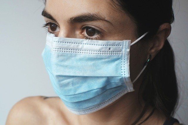 A woman is wearing a medical mask on her face.