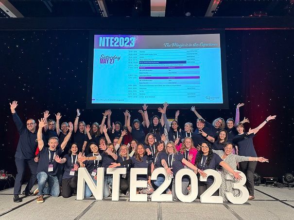 A group of people standing in front of a sign that says nte 2023