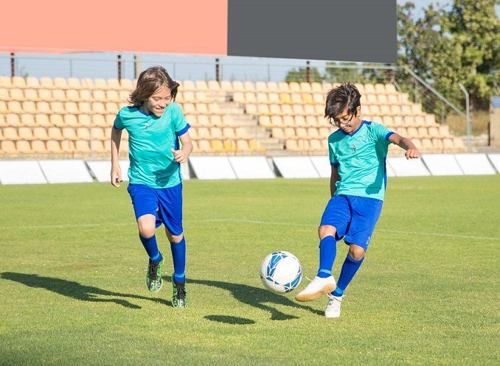 Two young boys are playing soccer on a soccer field.