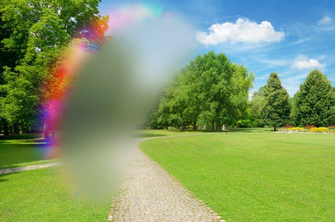 A blurry picture of a park with a rainbow in the background.
