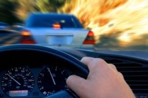 A person is driving a car and looking at the speedometer