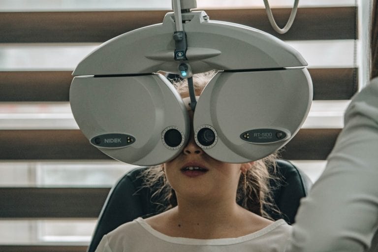 A young girl is getting her eyes checked by an ophthalmologist.