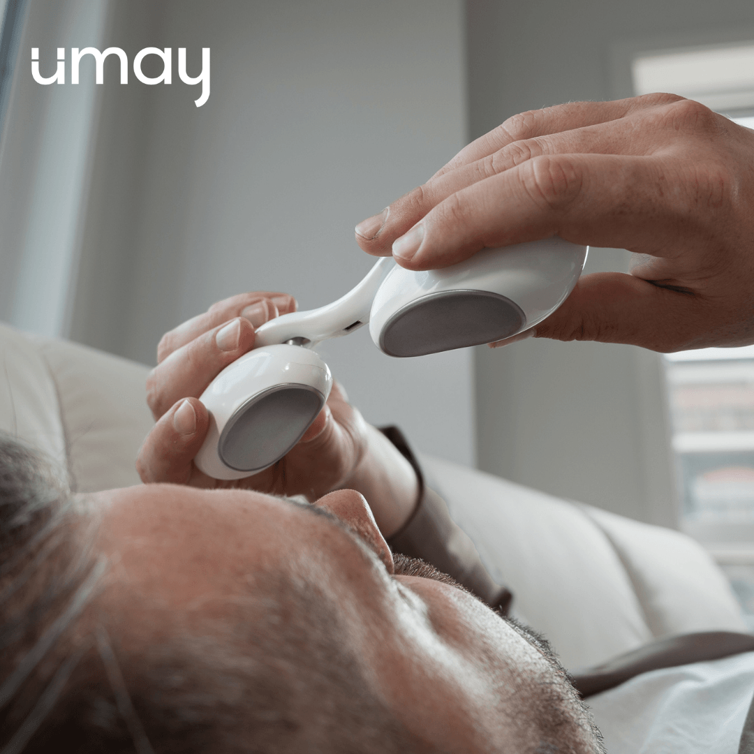 A man is laying on a couch holding a device that says umay