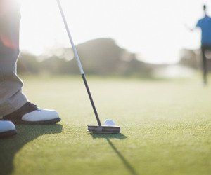 A person is putting a golf ball on a green.