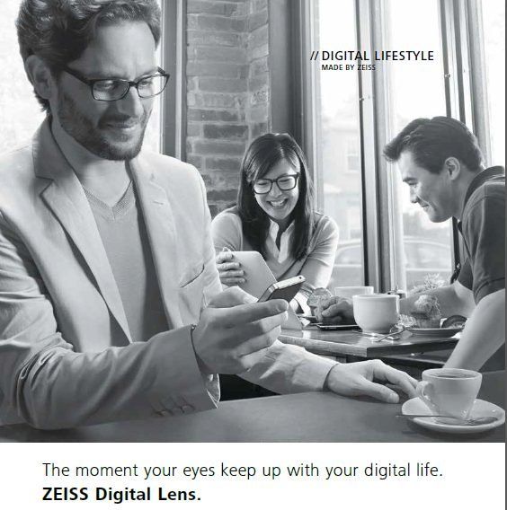 A man wearing glasses sits at a table with two other people