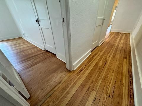 Wooden hallway with two white doors and different floor finishes meeting at a corner