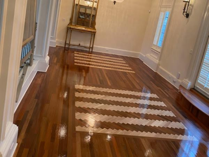 Partially refinished hardwood floor with light and dark wood tones in a room