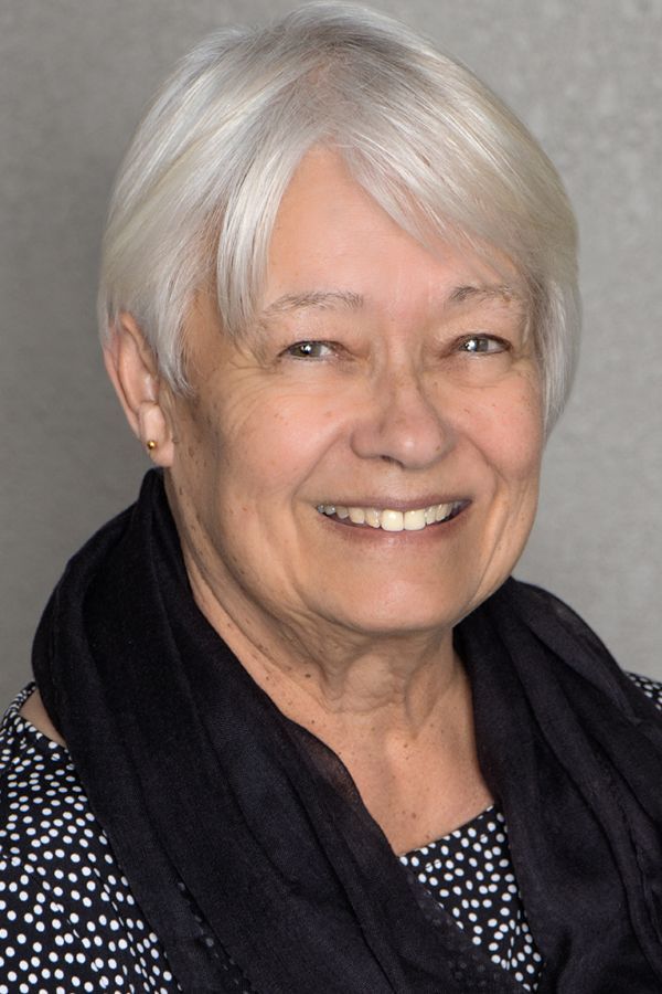 The woman is wearing a black scarf around her neck and smiling for the camera.