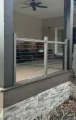 Covered backyard deck with gray posts, ceiling fan, and stairs leading down to a gravel path.