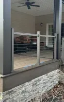Covered backyard deck with gray posts, ceiling fan, and stairs leading down to a gravel path.