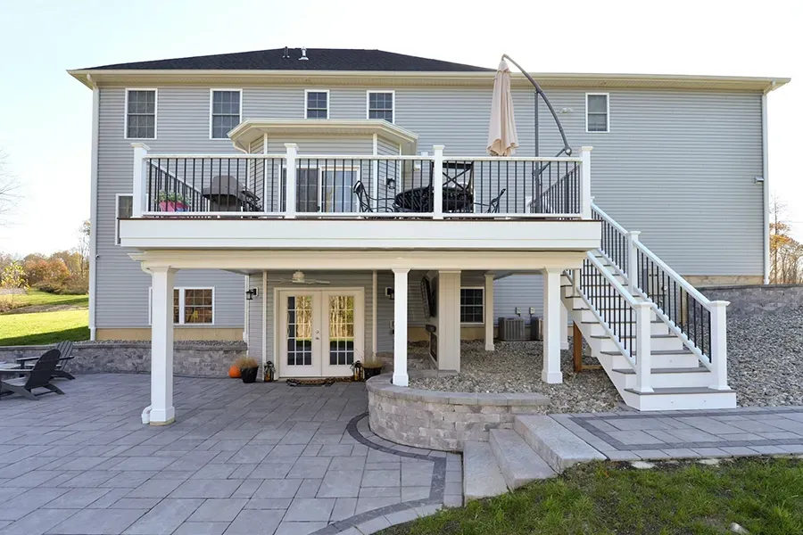 House exterior with raised deck, staircase, patio, and double doors