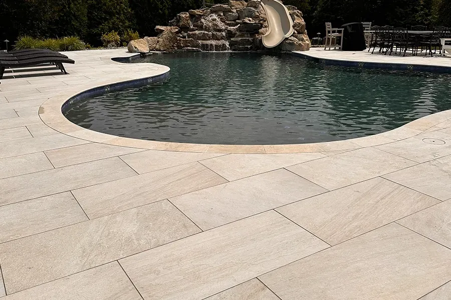 Backyard swimming pool with stone patio and rock waterfall slide