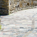 Stone-paved winding path beside rustic stone buildings on a sunny day
