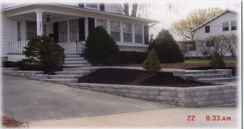 Suburban house with porch, front steps, shrubs, and driveway on a snowy or frosty morning.