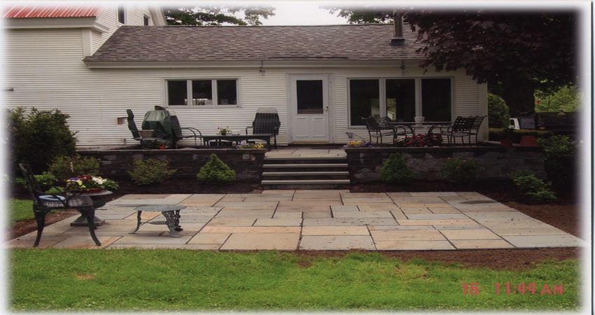 Front view of a single-story house with a patio, steps, and lawn in front