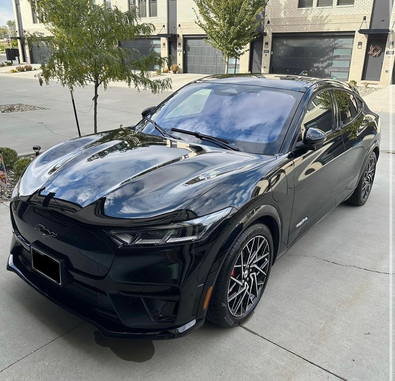Black sports coupe parked in a driveway in front of a house, angled front-left view.