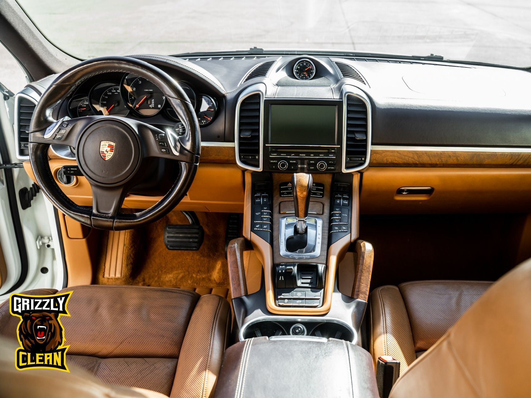 The interior of a porsche cayenne with brown leather seats and a steering wheel.
