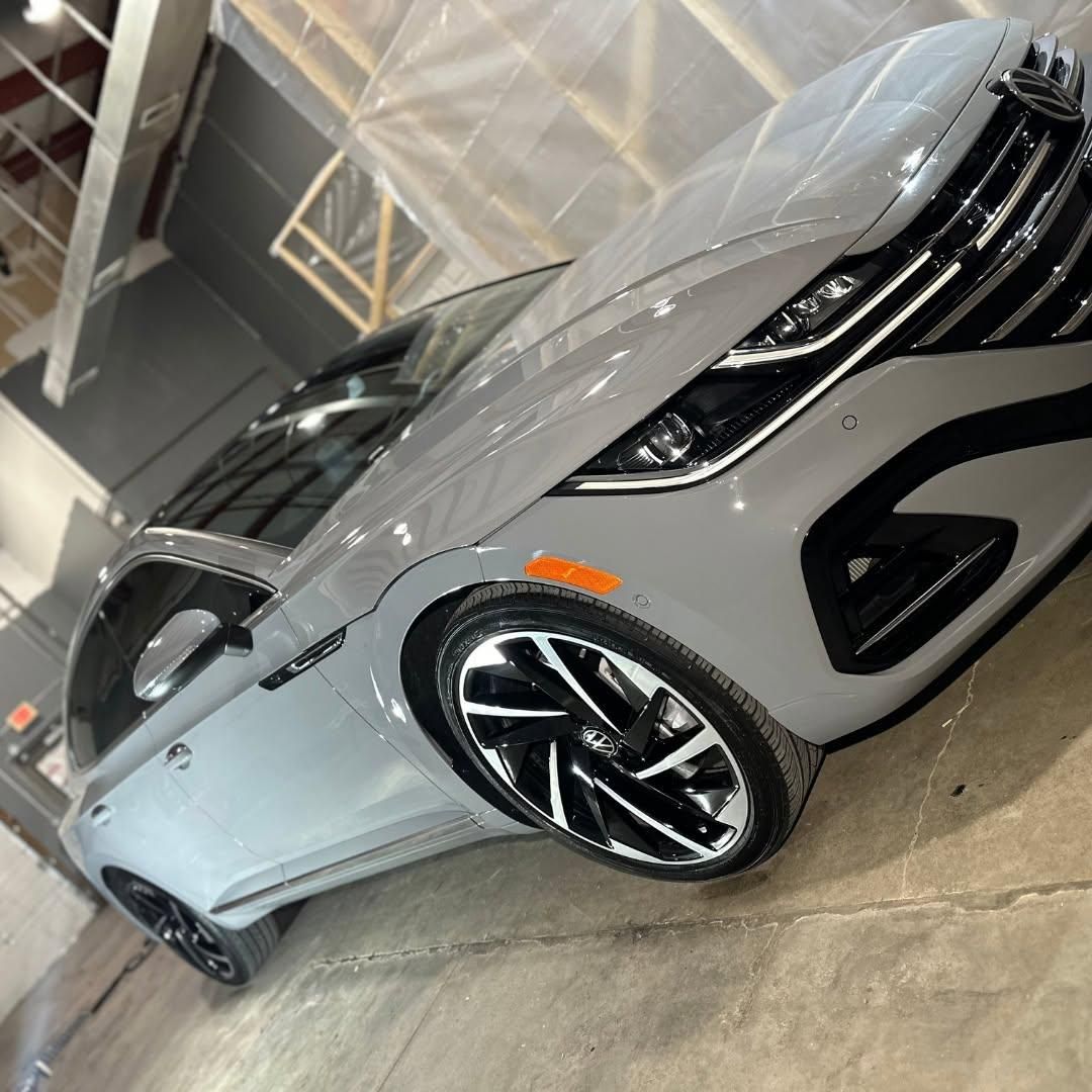 Silver sports sedan in a showroom, angled view with black accents and large alloy wheels.