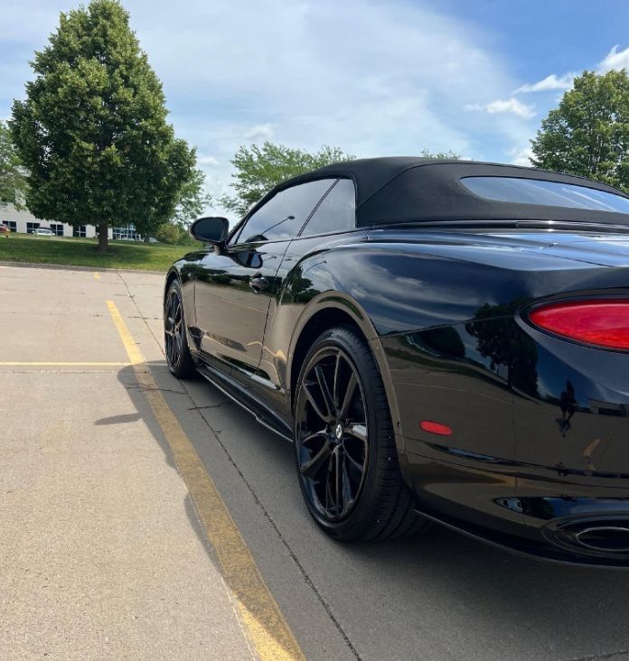 Black convertible sports car parked in a lot on a sunny day, rear three-quarter view