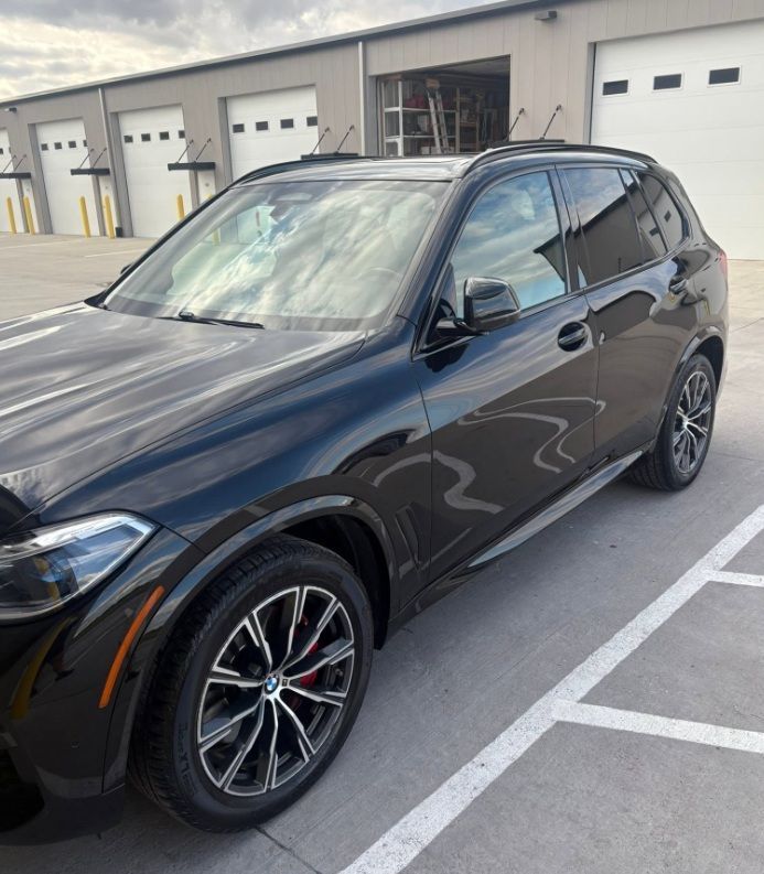 Dark blue SUV parked outside a building with garage doors.