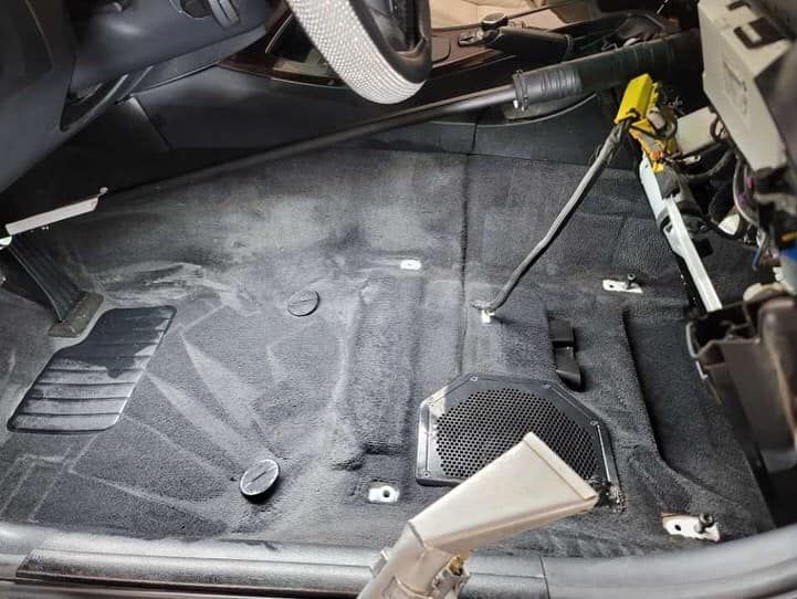 A vacuum cleaner is cleaning the floor of a car.