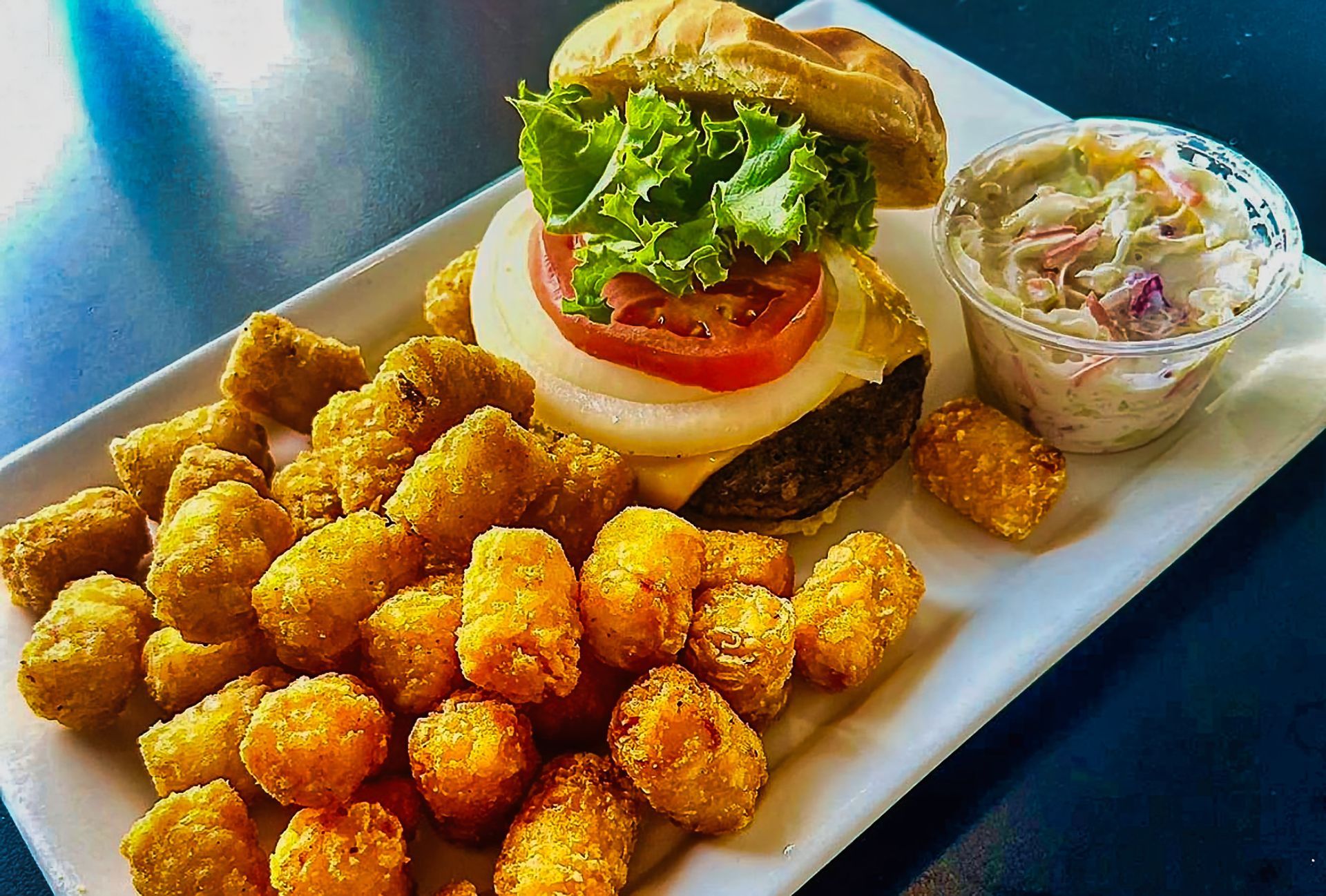 Fried chicken bites, burger, and coleslaw on a white platter