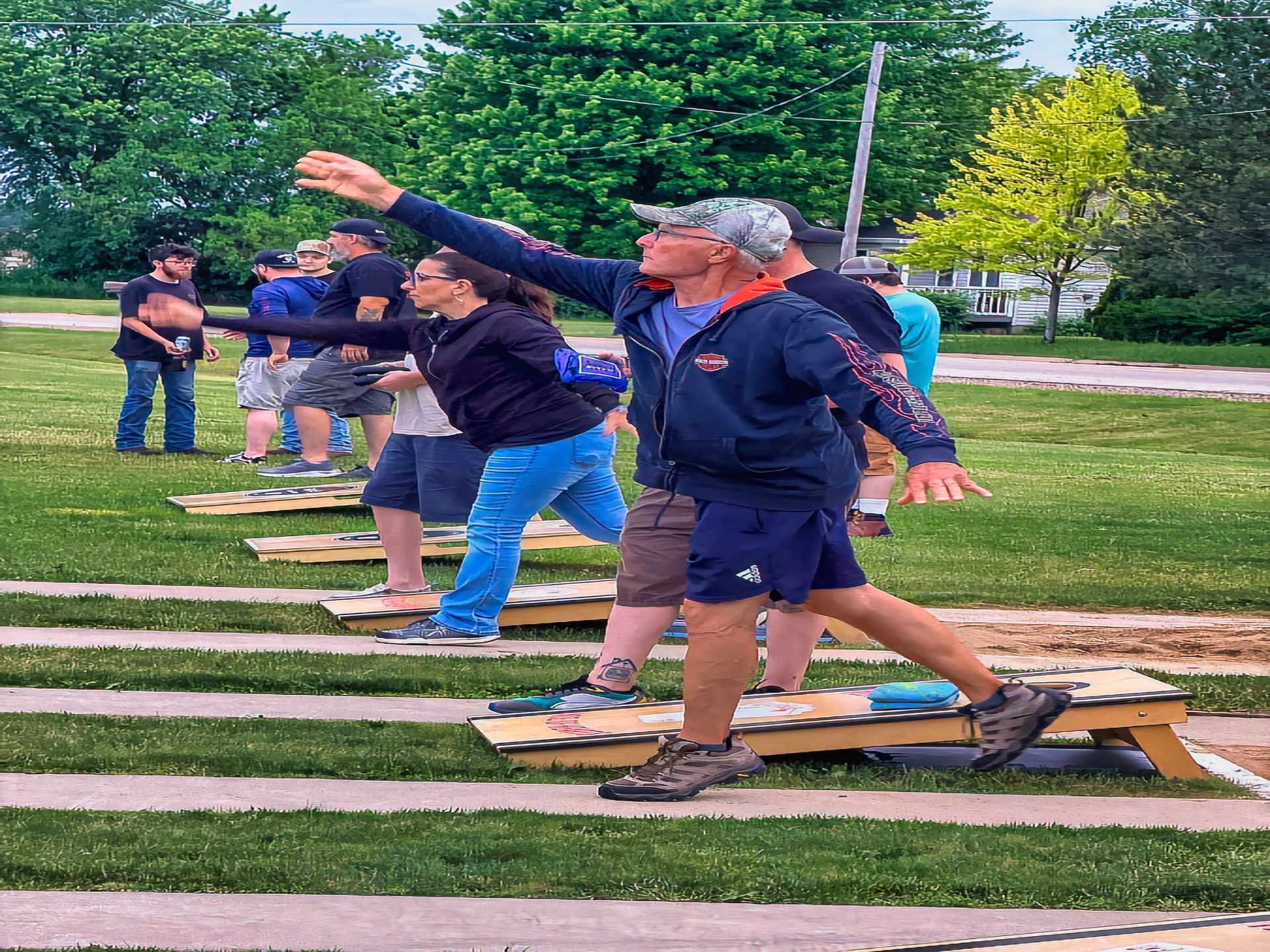 People on mats outdoors practicing a group stretch with arms extended forward.