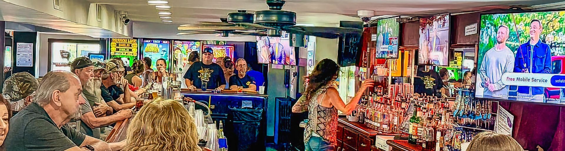 Crowded bar with people eating, colorful decorations, and bright TV screens in the background