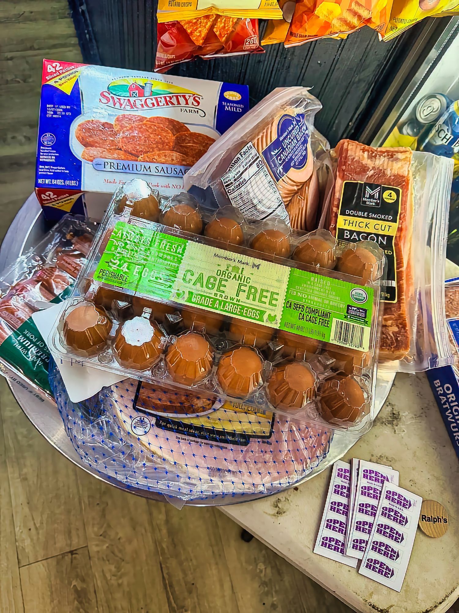 Assorted pastries and bread in plastic packaging displayed on a tray at a market stall.