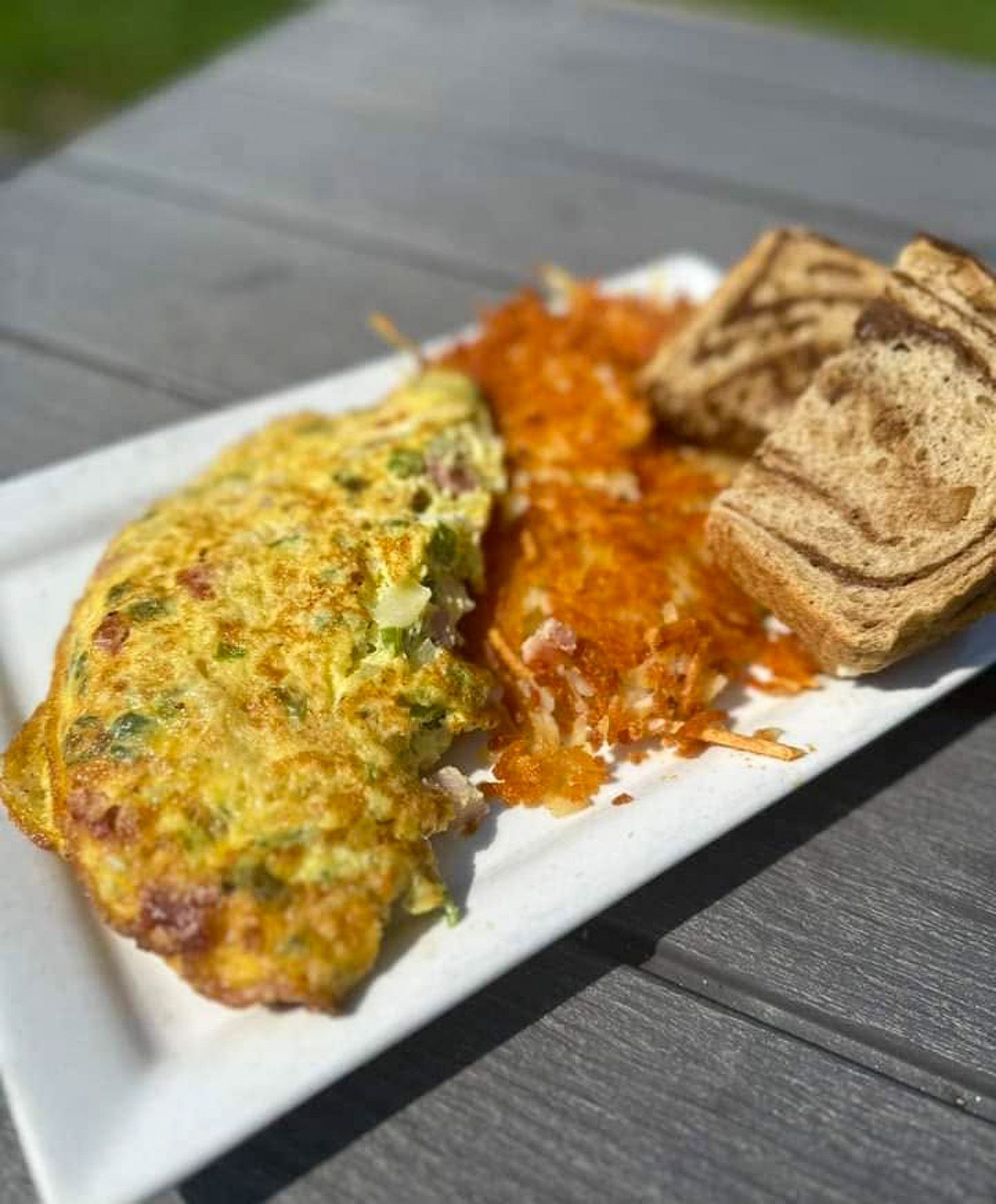 Omelet with salsa and toasted bread on a white plate outdoors